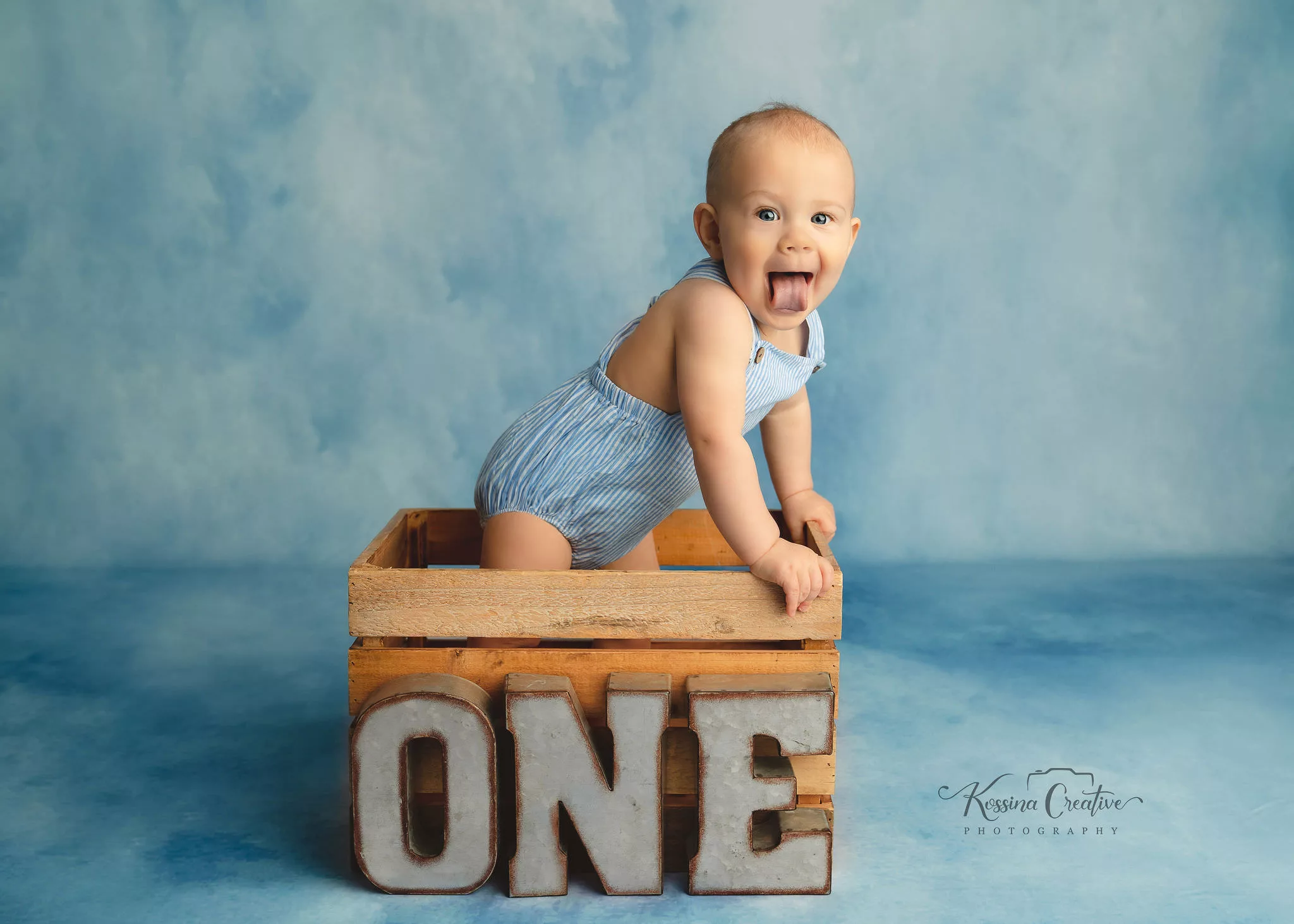 Orlando Boy Cake Smash 1st Birthday Photographer Photo Studio water color blue background one letters baby standing in crate tongue out
